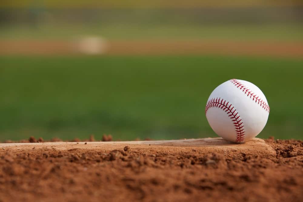 A baseball sitting on home plate of a baseball diamond