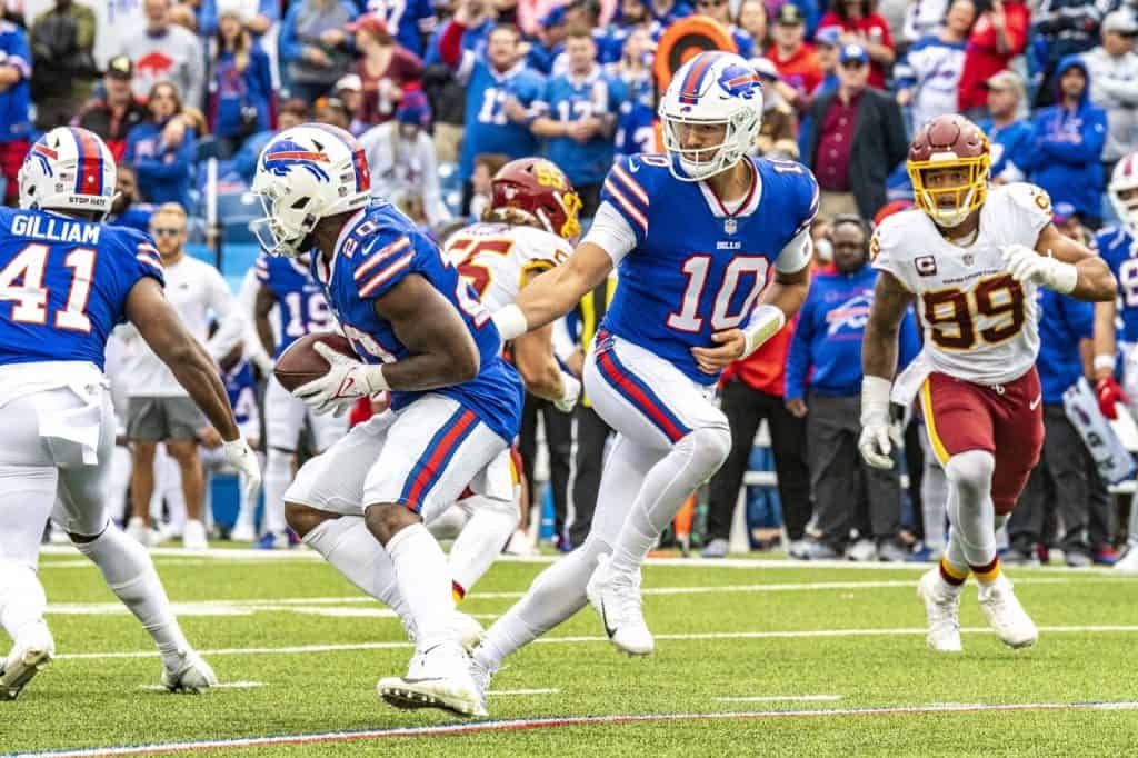 Mitch Trubisky, backup quarterback with the Buffalo Bills hands the ball off to his running back during a game against the Washington Football Team at Highmark Stadium in Buffalo, New York on September 26, 2021.