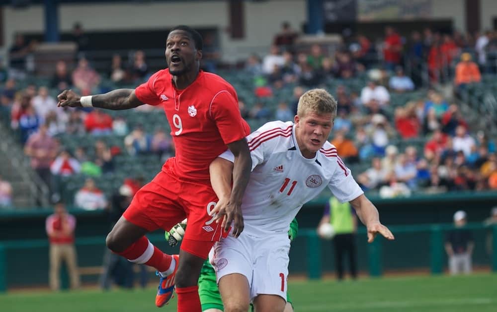 Tosaint Ricketts (Canada) drops back to help on a corner and rises above Andreas Cornelius (Denmark) to head the ball to safety