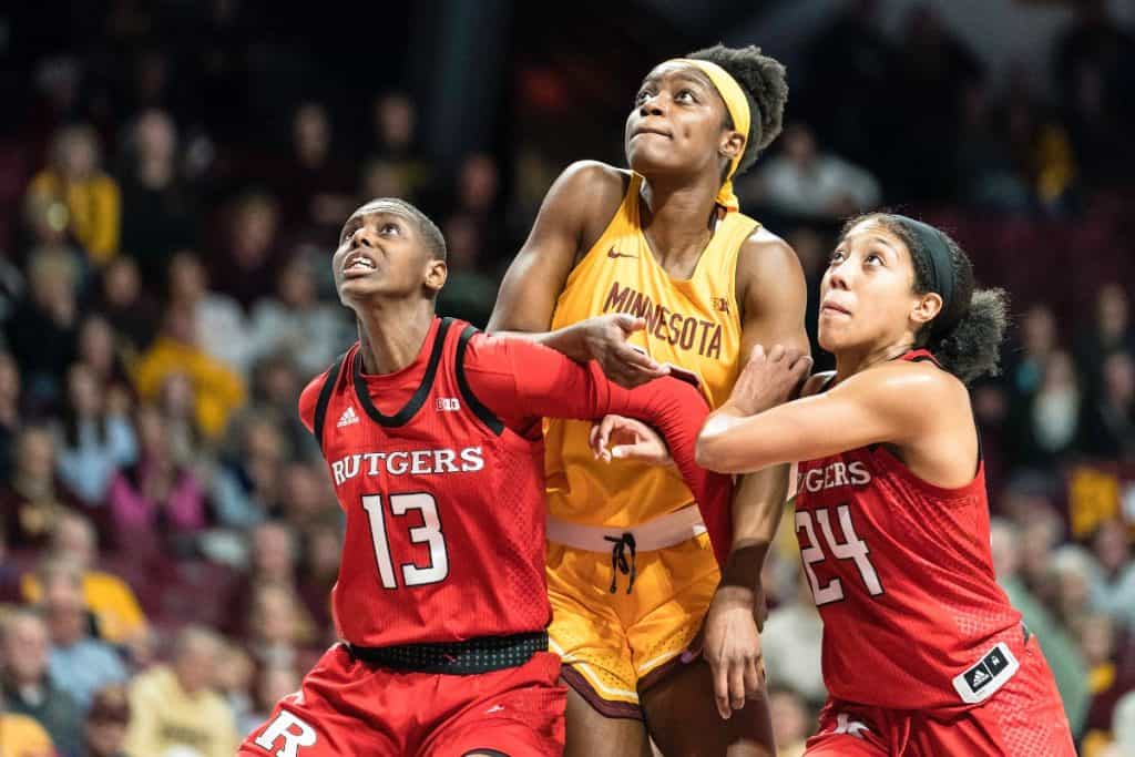 Kehinde Bello (Minnesota) looks for a rebound and is guarded by Mael Gilles and Arella Guirantes (Rutgers)